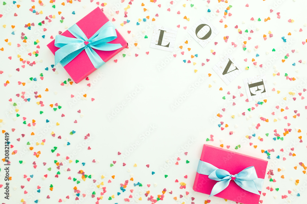 Valentines day composition with Love word, gifts and colorful confetti on white background. Copy space. Flat lay