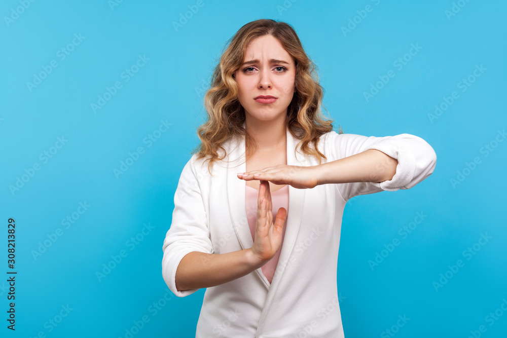 Time out! Portrait of worried tired woman with wavy hair in white jacket frowning in displeasure and making break or pause gesture, need stop, asking for rest. studio shot isolated on blue background Time out! Portrait of worried tired woman with wavy hair in white jacket frowning in displeasure and making break or pause gesture, need stop, asking for rest. studio shot isolated on blue background