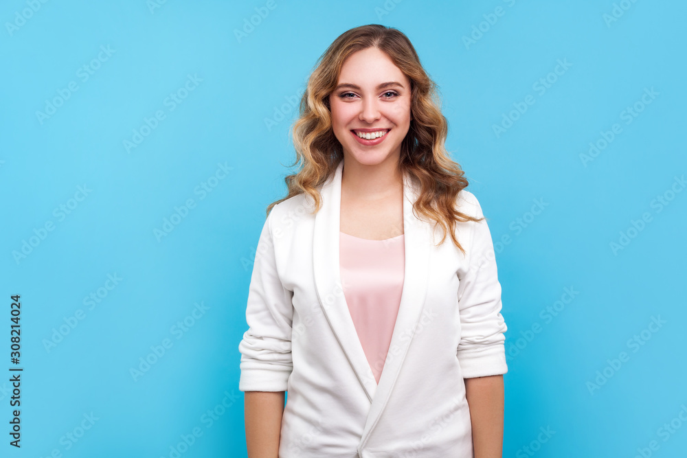 Portrait of vivid positive lovely bright businesswoman wearing casual white jacket looking at camera with perfect teeth smile, filled with joy optimism. indoor studio shot isolated on blue background Portrait of vivid positive lovely bright businesswoman wearing casual white jacket looking at camera with perfect teeth smile, filled with joy optimism. indoor studio shot isolated on blue background