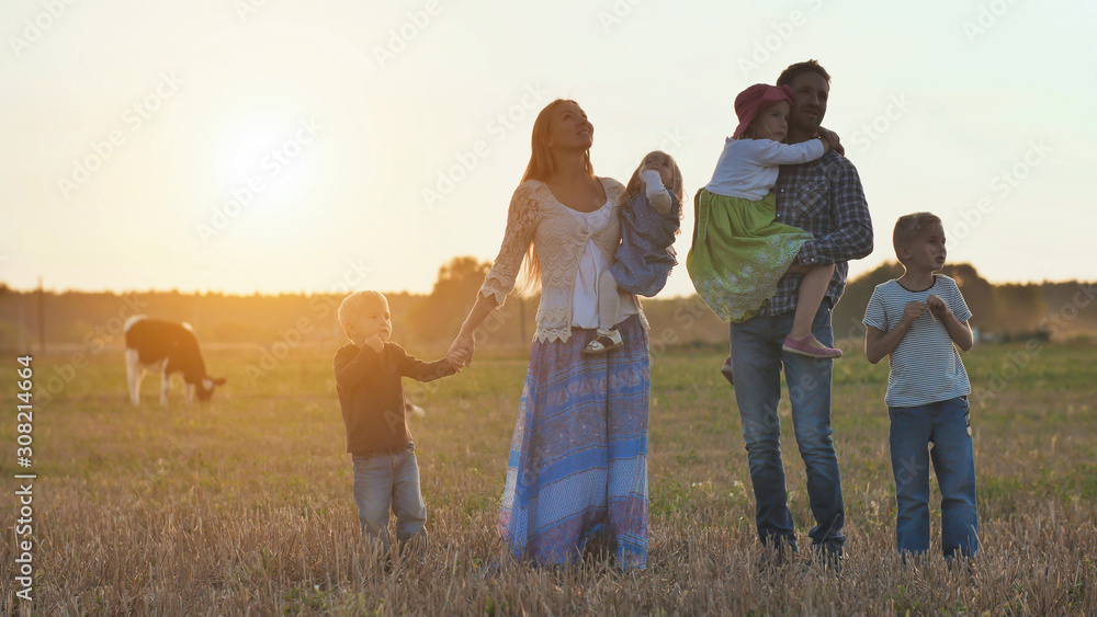 A large family goes on the field in the village during sunset. A large family goes on the field in the village during sunset.