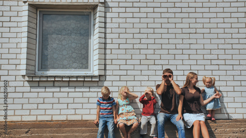Obraz premium A large family with four children in front of their own home.