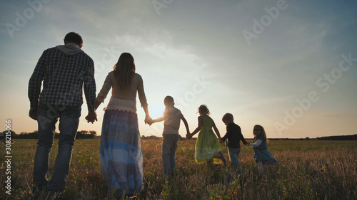 A large family of six people walk on the floor at sunset.