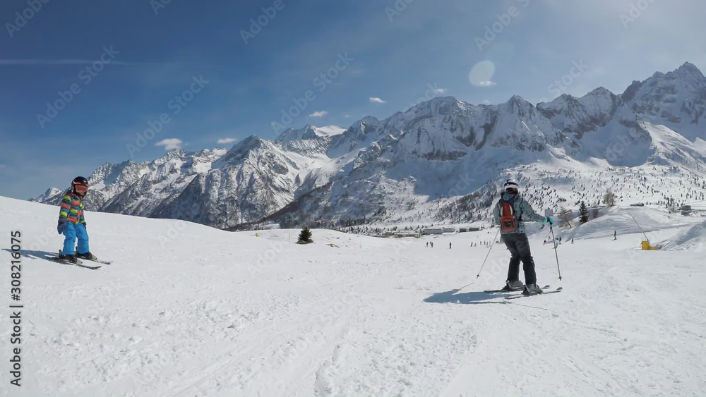 Little boy skiing in the Alpine resort..A 6 year old child enjoys a winter holiday with his mother. .