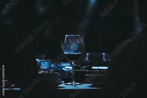 Closeup to wine glass at night party of wedding ceremony in dark tone.