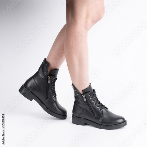 demi seasonal female leather black shoes with lacing on model legs shot in studio on a white background. Beautiful stylish pair of shoes for catalog
