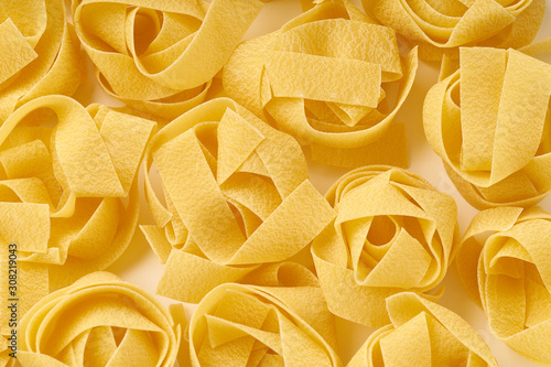 Closeup with raw papardelle pasta nests on white background