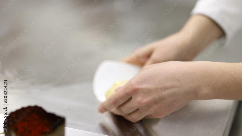 a pastry chef in a white tunic forms a panettone dough with a scraper with his hands a pastry chef in a white tunic forms a panettone dough with a scraper with his hands