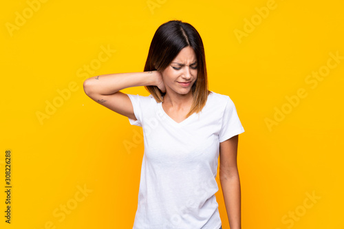 Young woman over isolated yellow background with neckache