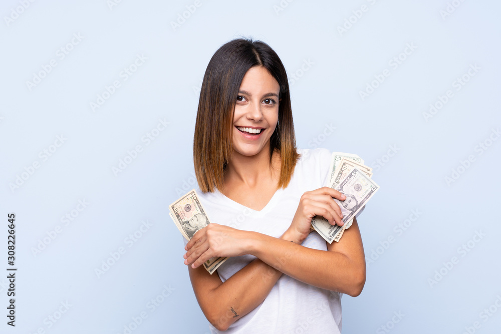 Young woman over isolated blue background taking a lot of money Young woman over isolated blue background taking a lot of money