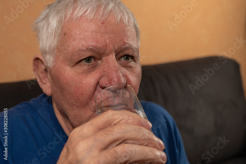 Senior trinkt aus einem Glas Wasser