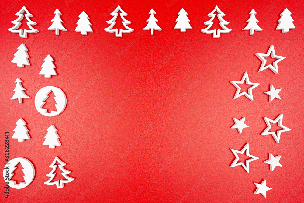 Wooden, white Christmas trees and stars arranged sideways and upwards, isolated on a red background.