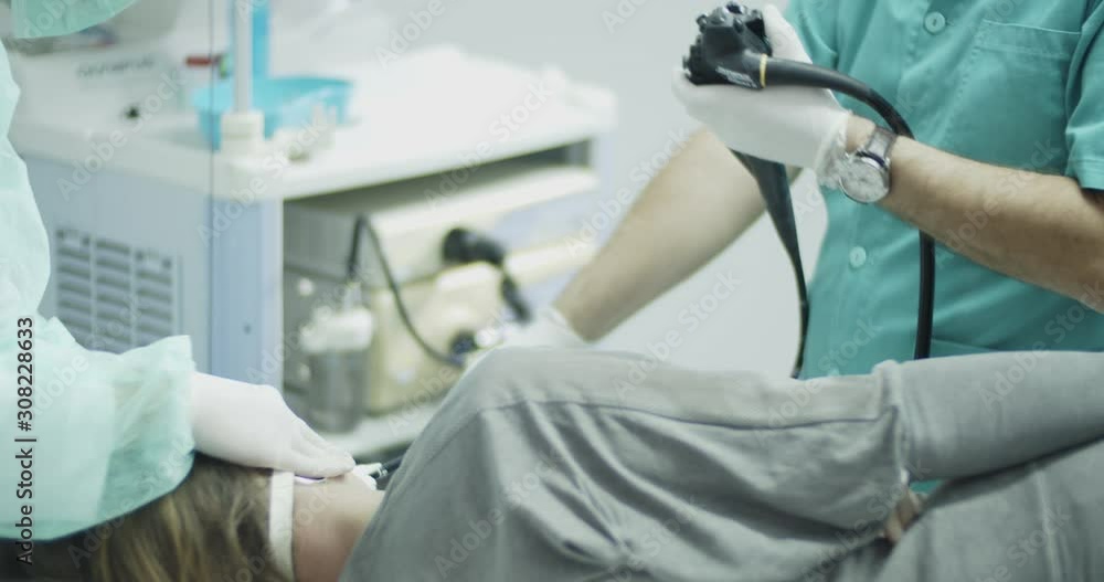 Female patient lying on bed during gastrologist performing endoscopy examination in the office room.