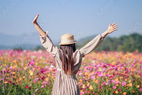 Billede på lærred An Asian woman in a vintage style is stretching,To chase away the feeling of sleepiness after waking up in the morning to see the beautiful cosmos field The girl feels sleepy after waking up early