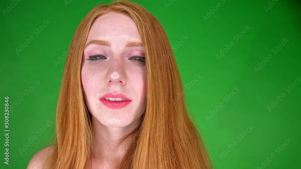 A close up portrait of a beautiful young white woman, smiling and looking straight into camera. Green background. Slow motion. A close up portrait of a beautiful young white woman, smiling and looking straight into camera. Green background. Slow motion.