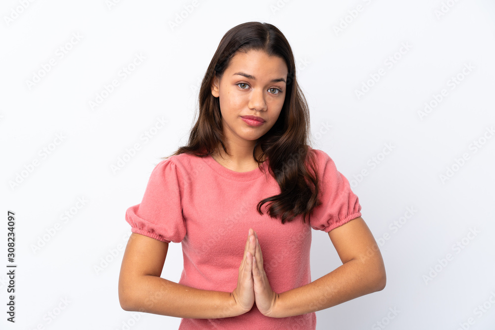 Young Colombian girl over isolated white background keeps palm together. Person asks for something Young Colombian girl over isolated white background keeps palm together. Person asks for something