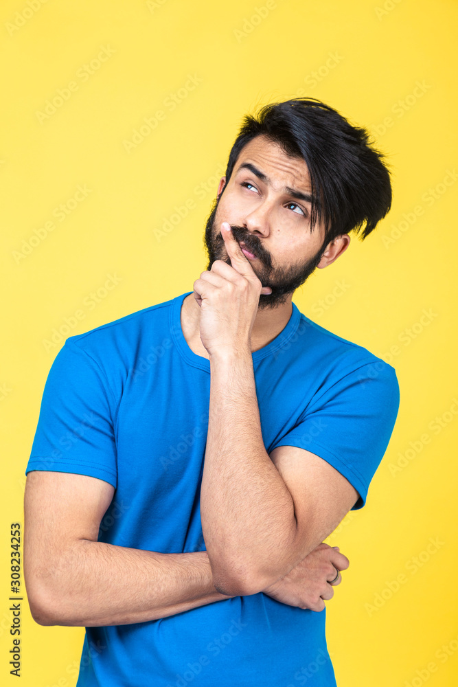 Emotional portrait of a Hindu man in a blue T-shirt on a yellow background Emotional portrait of a Hindu man in a blue T-shirt on a yellow background