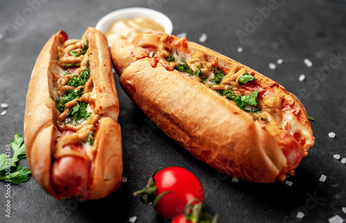 french hot dogs baked with cheese and mustard on a stone background