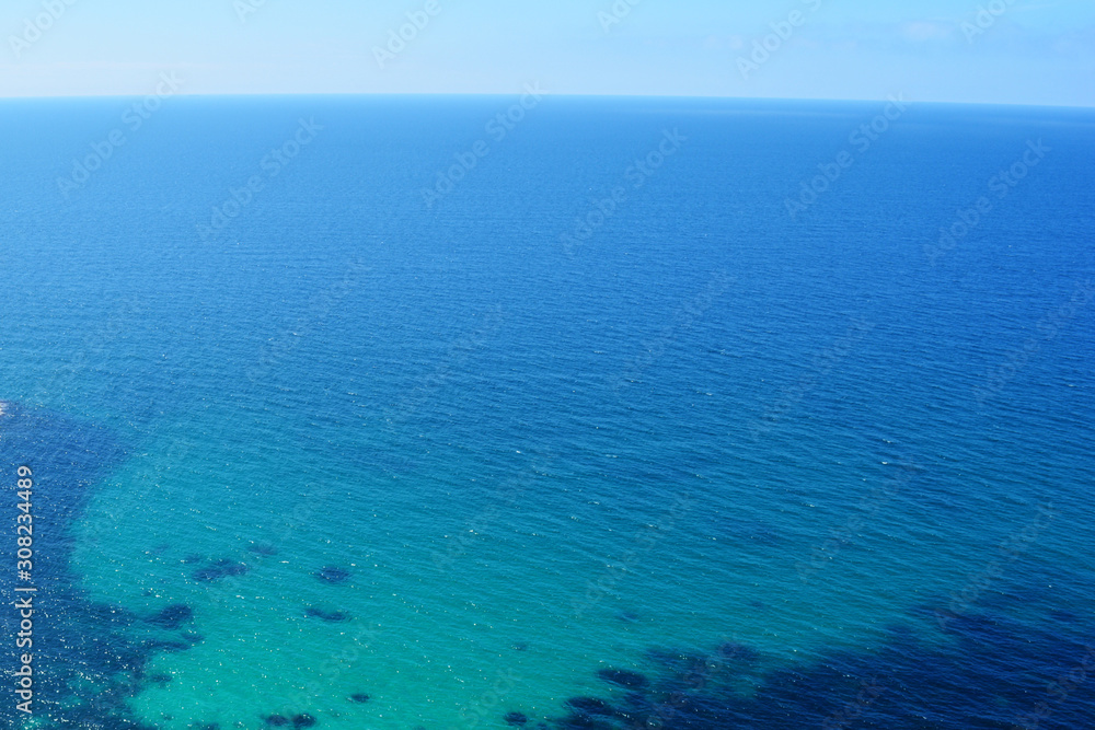 Texture of sea shore with clear turquoise water and sandy bottom. Sea surface aerial top view. Summer beautiful Background.