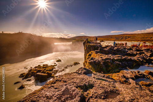 Goðafoss in long exposer, blue sky, warm autumn colors in the sun photo