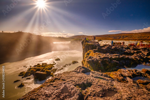 Goðafoss in long exposer, blue sky, warm autumn colors in the Sun rays 