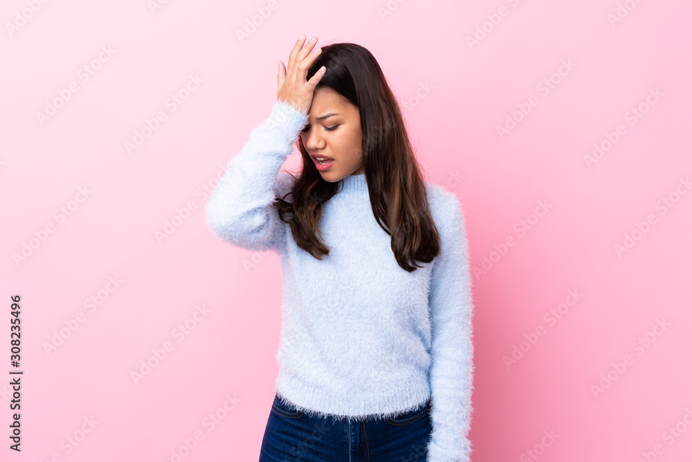 Young Colombian girl over isolated pink background having doubts with confuse face expression Young Colombian girl over isolated pink background having doubts with confuse face expression