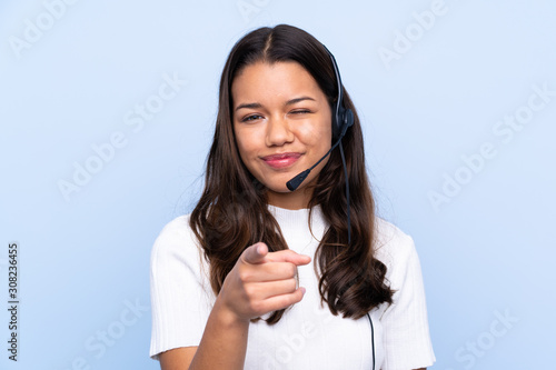 Young telemarketer Colombian woman over isolated blue background points finger at you photo