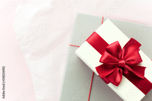 Gift box/ present with red bow on white/pink background. Festive backdrop for holidays: Birthday, Valentines day, Christmas, New Year. Flat lay