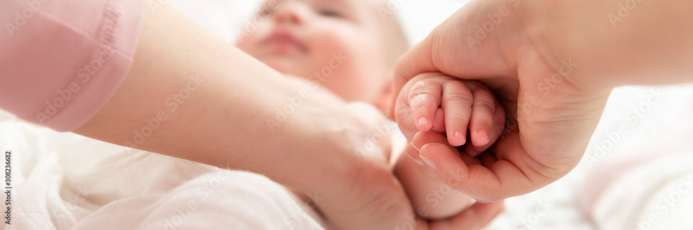 Mother gently massaging her baby boy while applying body lotion to his skin. Baby massage banner. Hands close up. Mother gently massaging her baby boy while applying body lotion to his skin. Baby massage banner. Hands close up.