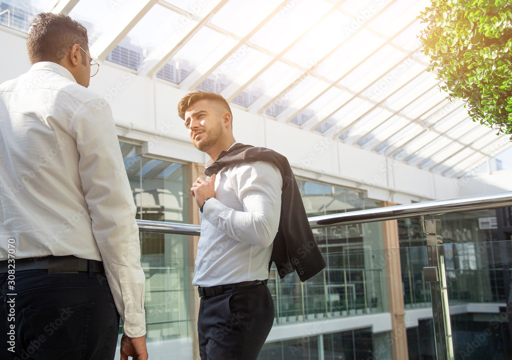 young business people are standing and talking on the background of glass offices. Corporate businessteam and manager in a meeting. young business people are standing and talking on the background of glass offices. Corporate businessteam and manager in a meeting.