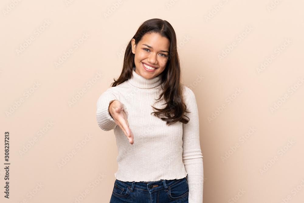 Young Colombian girl over isolated background shaking hands for closing a good deal Young Colombian girl over isolated background shaking hands for closing a good deal