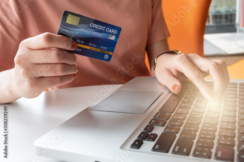 Fototapeta Naklejka Na Ścianę i Meble -  Close up of someone hand holding credit card during using laptop for online shopping. Online shopping is the process of buying goods and services from merchants over the Internet.