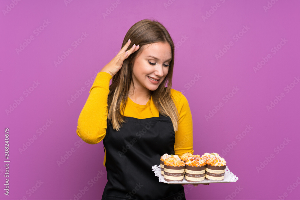 Teenager girl holding lots of different mini cakes over isolated purple background laughing Teenager girl holding lots of different mini cakes over isolated purple background laughing