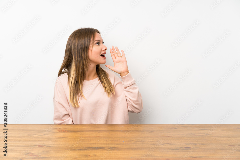 Teenager girl in a table shouting with mouth wide open Teenager girl in a table shouting with mouth wide open