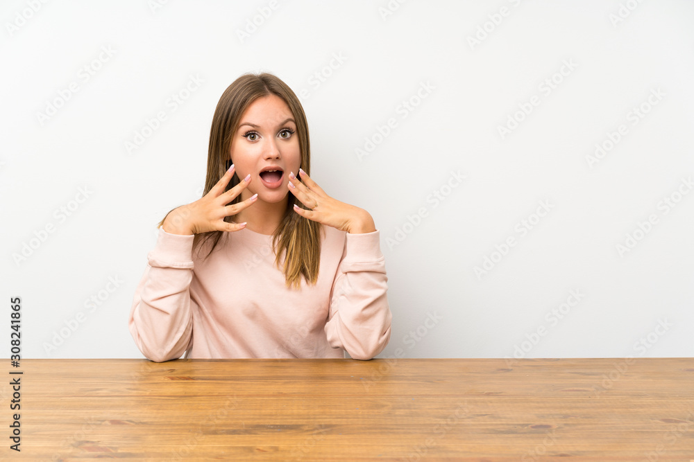 Teenager girl in a table with surprise facial expression Teenager girl in a table with surprise facial expression