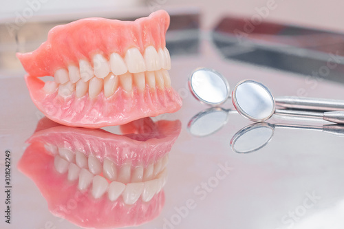Two dentures.  Instruments and dental hygienist checkup concept with teeth model dentures and mouth mirror. Regular dentist checkups
