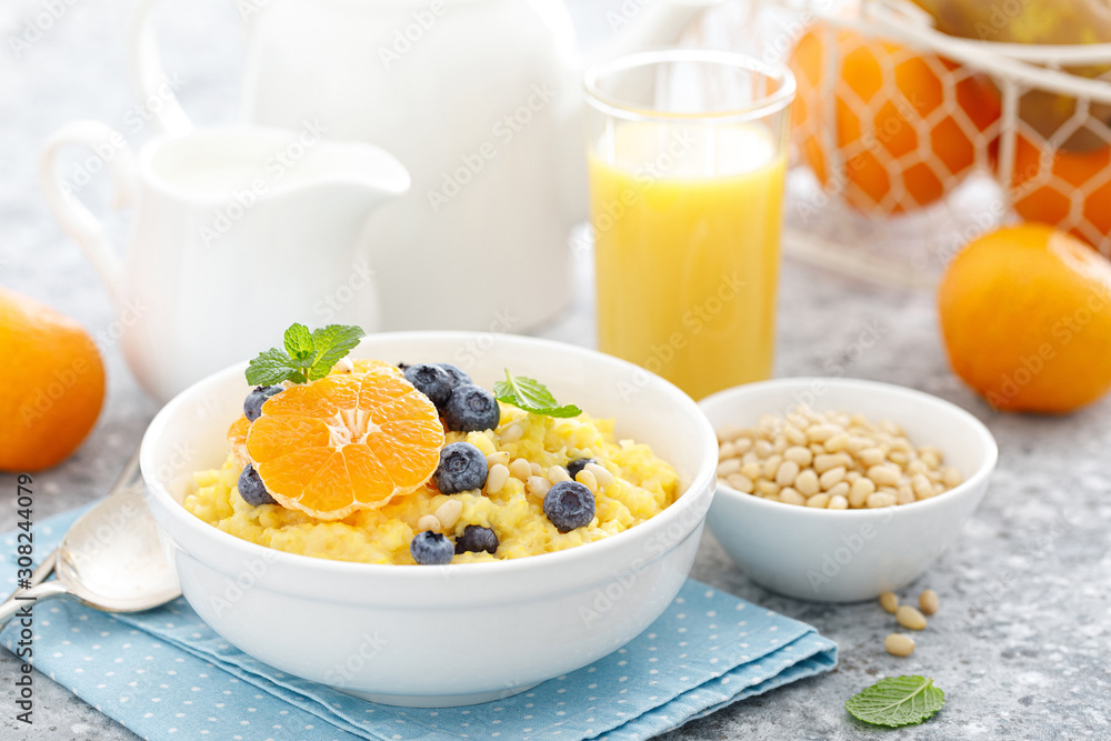 Corn porridge with fresh blueberry, orange and pine nuts in bowl served for breakfast Corn porridge with fresh blueberry, orange and pine nuts in bowl served for breakfast