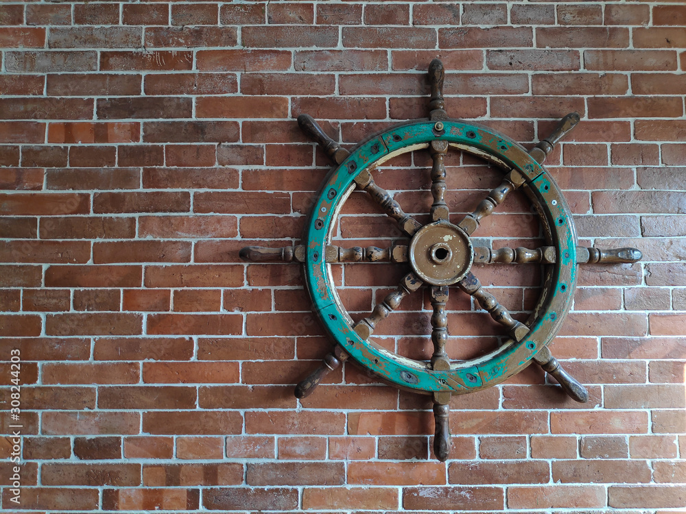 wooden boat/ship steering wheel hanging on the brick wall for decoration