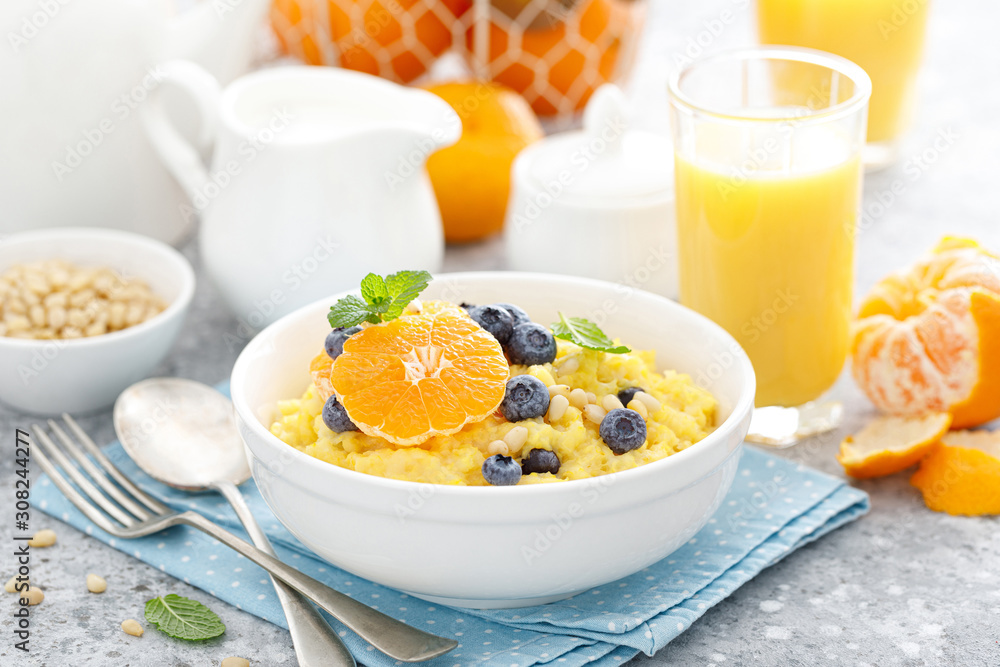 Corn porridge with fresh blueberry, orange and pine nuts in bowl served for breakfast Corn porridge with fresh blueberry, orange and pine nuts in bowl served for breakfast