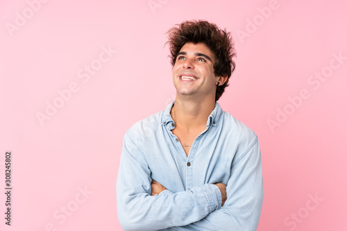 Young caucasian man with jean shirt over isolated pink background looking up while smiling