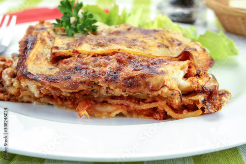 lasagna with bolognese and green salad on a plate