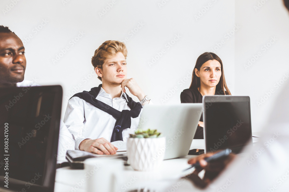 A team of young businessmen working and communicating together in an office. Corporate businessteam and manager in a meeting.
