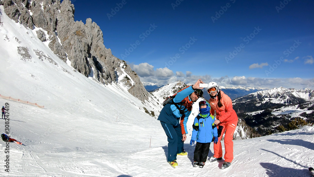 Family vacation in the ski resort. Parents taking selfie with their son.