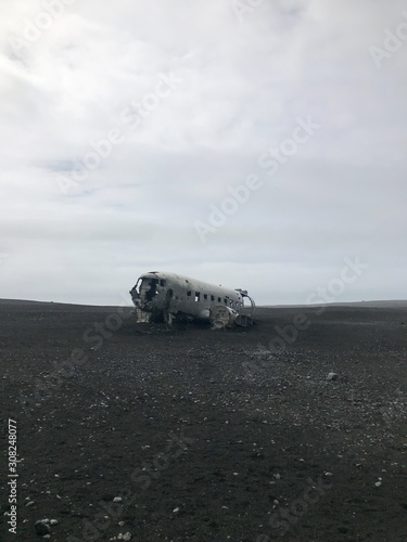 Crashed and abandoned plane on black sand