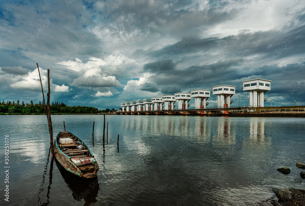 Obraz premium Fishing boat and water barrier and river with cloud sky storm in rain season