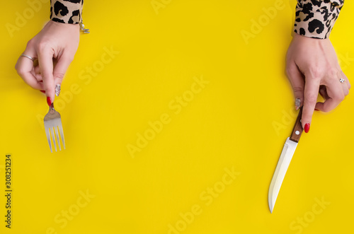 .Top view girl holding a fork and knife on a yellow background