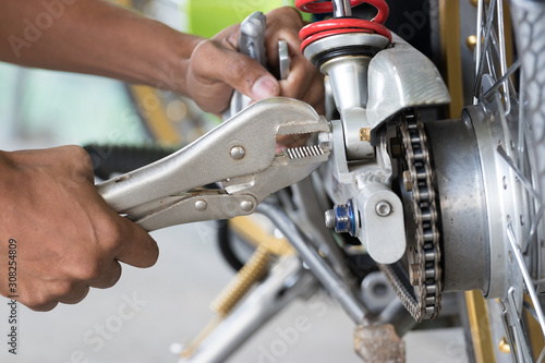 Technicians use locking pliers to unscrew screws to fix the motorcycle.