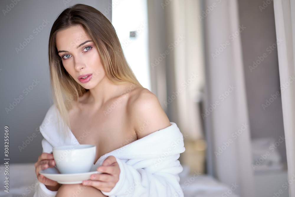 Enjoying morning coffee. Close-up of beautiful young woman holding cup while relaxing on couch at home Enjoying morning coffee. Close-up of beautiful young woman holding cup while relaxing on couch at home