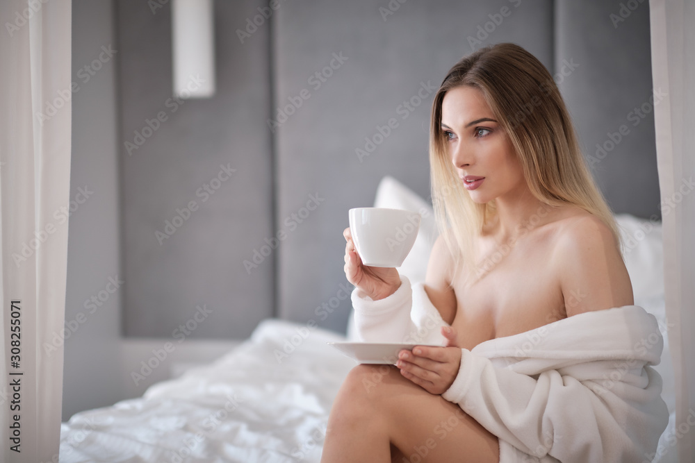Enjoying morning coffee. Close-up of beautiful young woman holding cup while relaxing on couch at home Enjoying morning coffee. Close-up of beautiful young woman holding cup while relaxing on couch at home