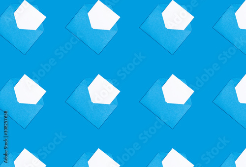 Trendy pattern made with white blank card in opened craft envelope blue background.