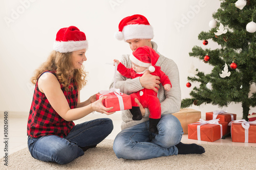 Happy couple with baby celebrating Christmas together at home.